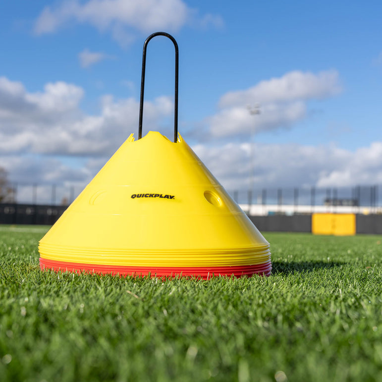 Yellow & red training cone stack on grass, branded 'QuickPlay', against a blue sky.