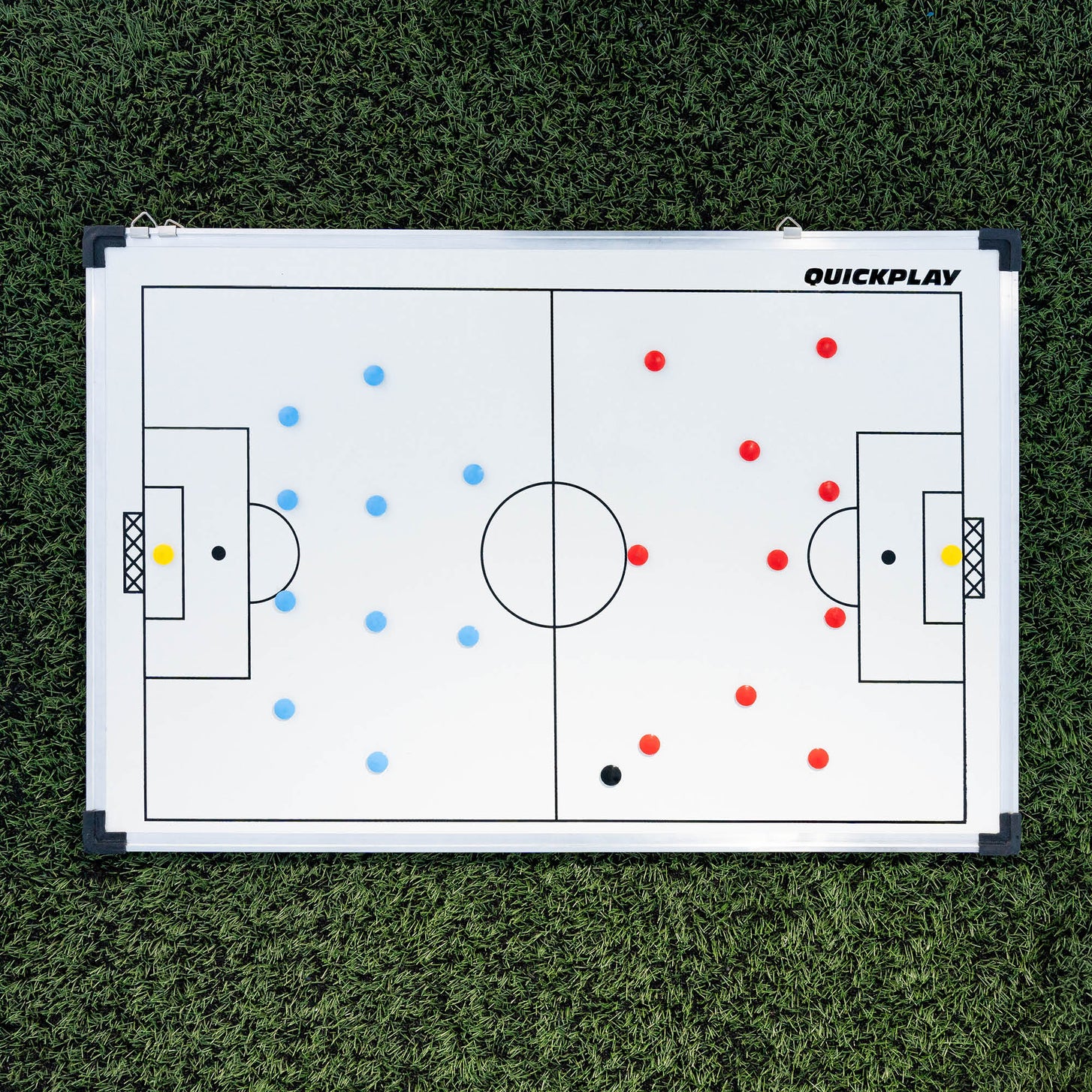 QUICKPLAY Magnetic Whiteboard (LG) 60x90cm flat on artificial grass, set out with red and blue team magnets.
