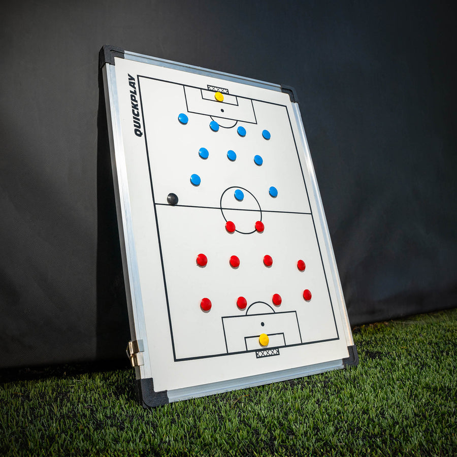 QUICKPLAY Magnetic Whiteboard (S) 30x45cm with red, blue and yellow magnets, leaning upright on artificial grass.