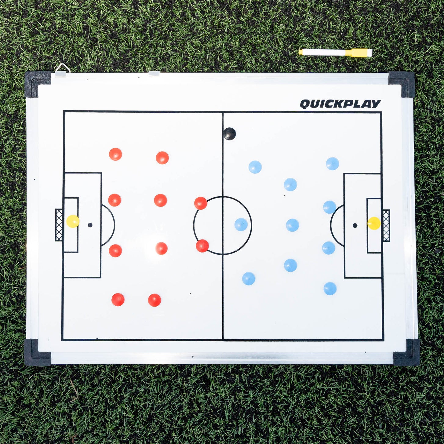 QUICKPLAY Magnetic Whiteboard (S) 30x45cm flat on artificial grass, with two teams of magnets and a yellow marker pen.