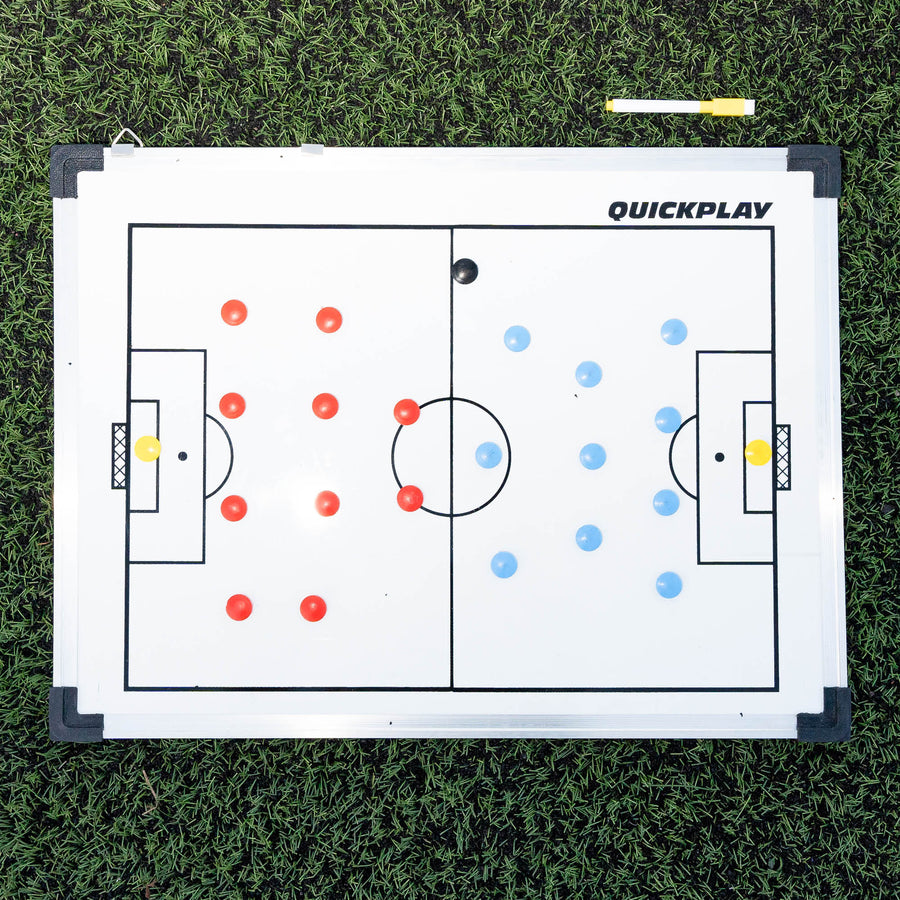 QUICKPLAY Magnetic Whiteboard (S) 30x45cm flat on artificial grass, with two teams of magnets and a yellow marker pen.