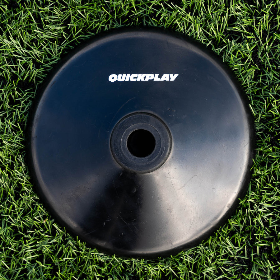 Single black QUICKPLAY training pole rubber base on artificial grass, seen from above with its centre hole.