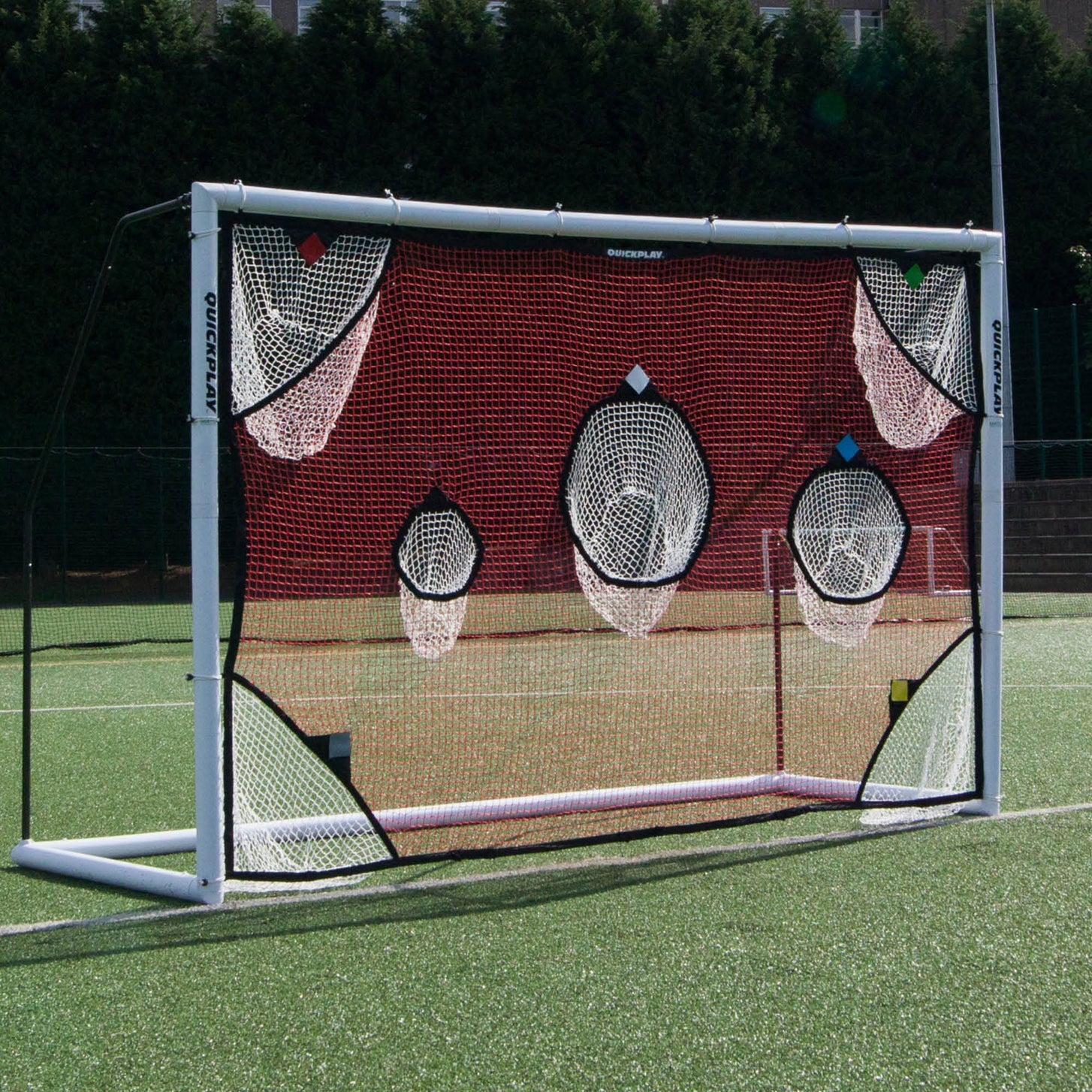 TARGET Net 3x2m with red netting and white catch pockets fitted to a white goal on an artificial pitch.