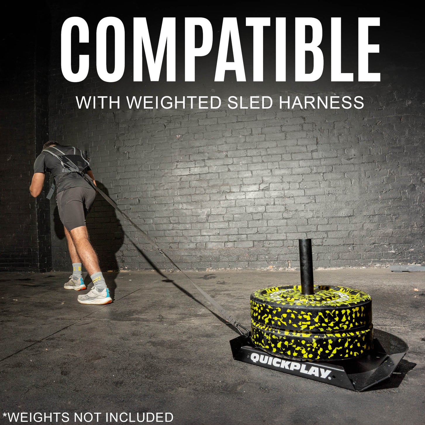 Man in a harness pulling the loaded Pull Speed Sled across a concrete floor, with the text "Compatible with weighted sled harness".