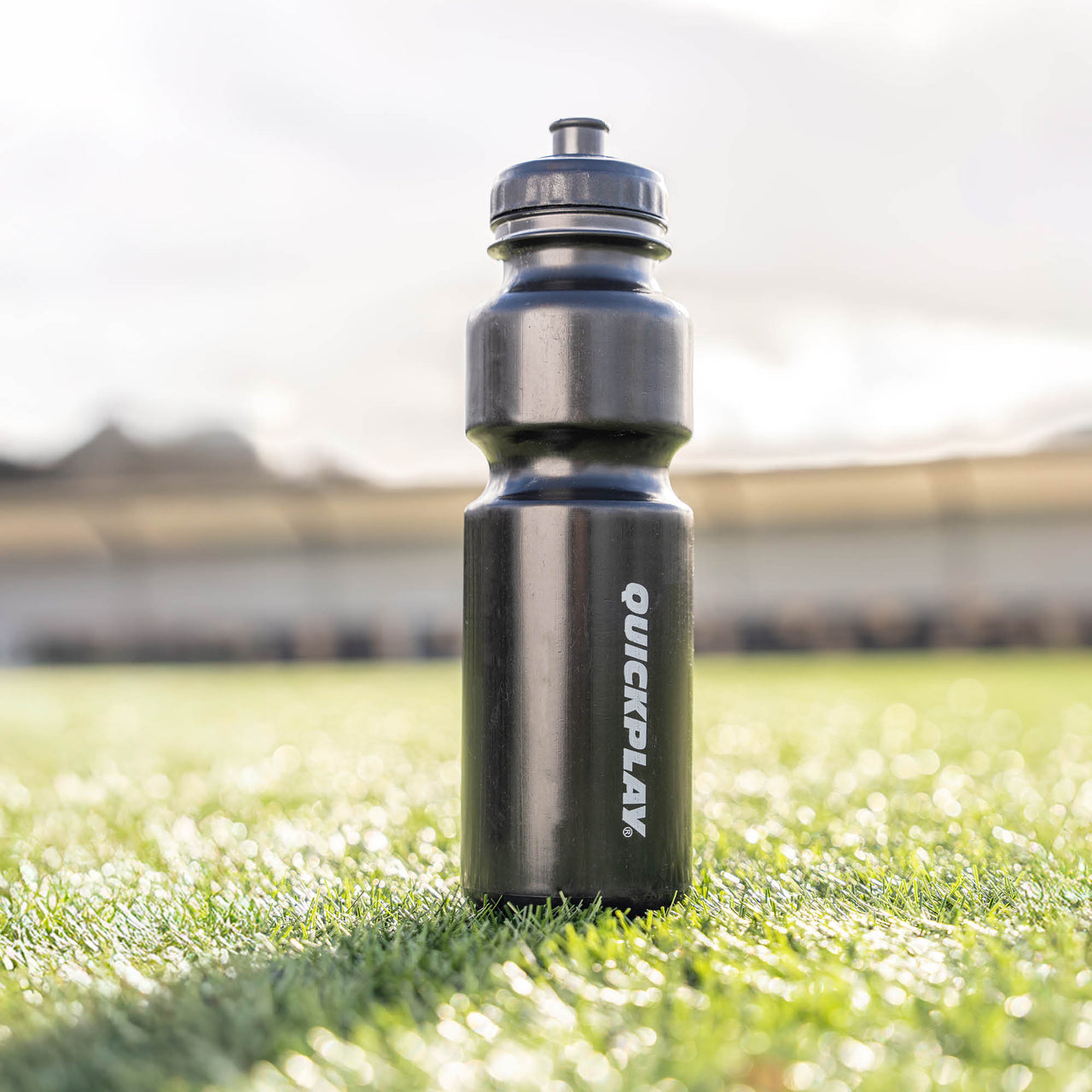 Black water bottle with 'QuickPlay' branding on grass