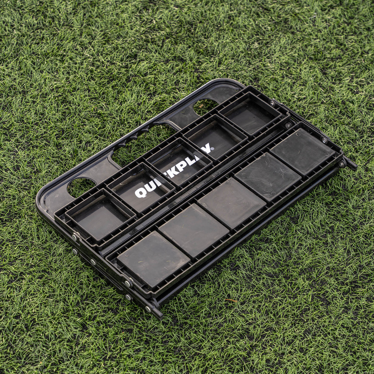 Black folded water bottle holder with compartments on a grassy background