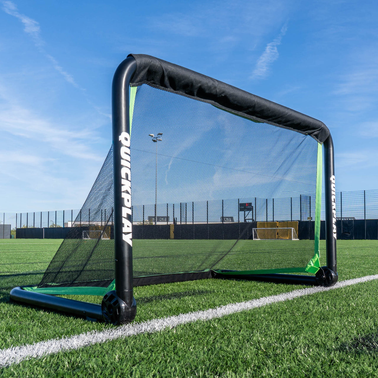 portable football goal on a grass field with a clear blue sky.