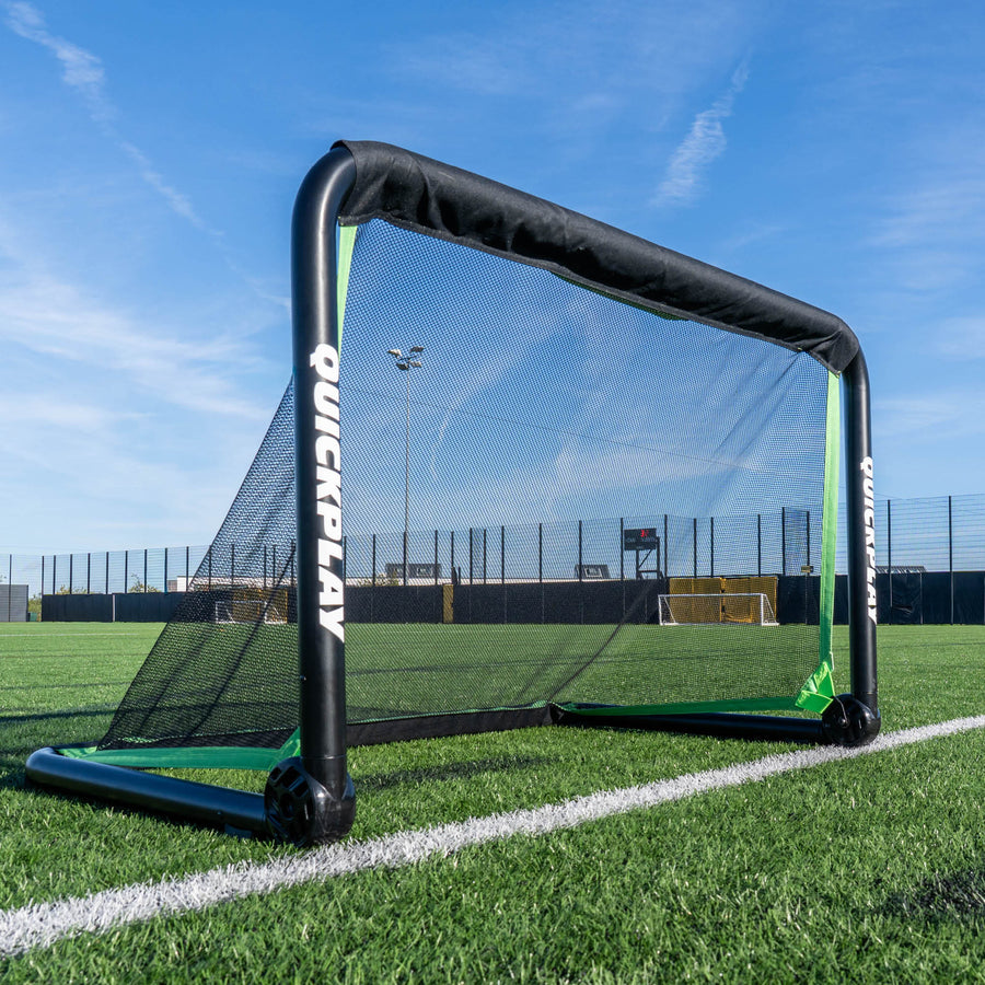 portable football goal on a grass field with a clear blue sky.