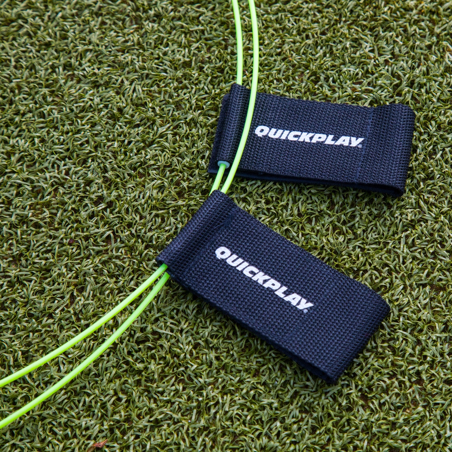 Two yellow-green KICKSTER Football Target Rings with black QUICKPLAY straps, close up on artificial grass.