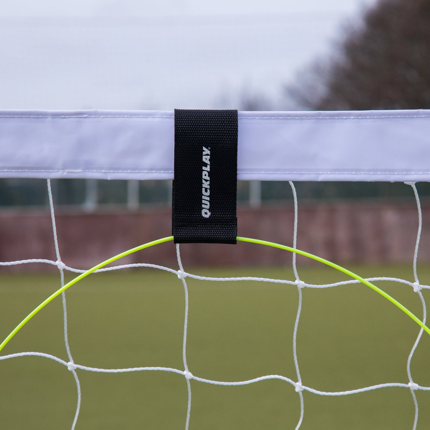 Close-up of a KICKSTER Football Target Ring hanging from a white goal crossbar by its black QUICKPLAY strap.