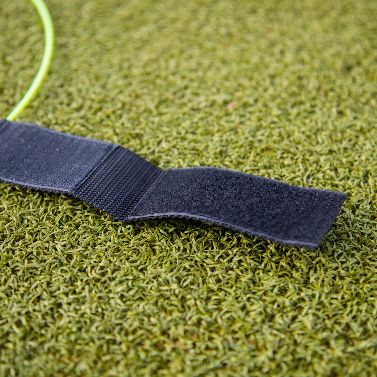 Close-up of the open black hook and loop strap on a KICKSTER Football Target Ring, on artificial grass.