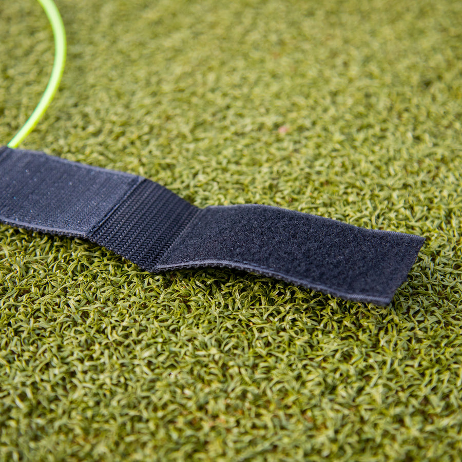 Close-up of the open black hook and loop strap on a KICKSTER Football Target Ring, on artificial grass.
