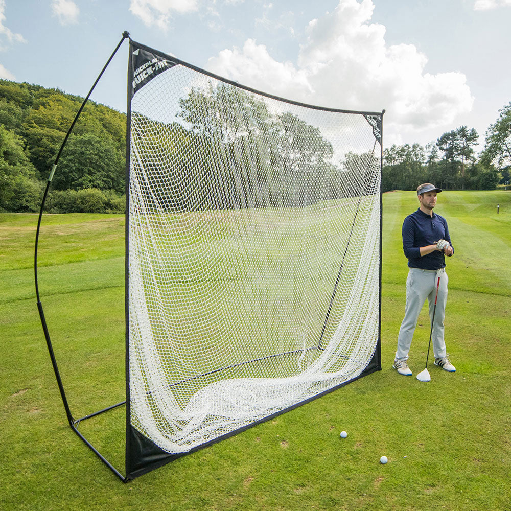 QUICK-HIT Golf Hitting Net 8x8' set up on a golf course with a golfer standing beside it holding a club.