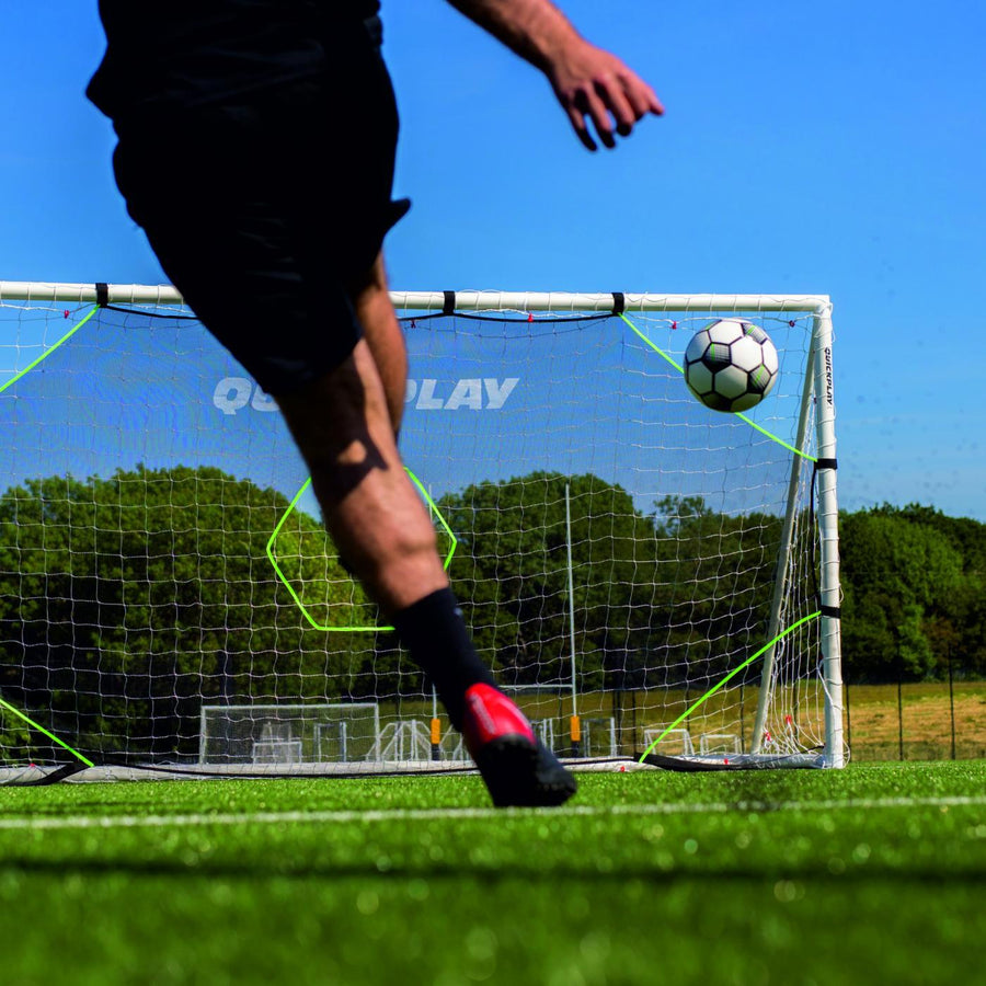 Player striking a ball towards the top corner of the TARGET Net Lite 16x7' on an artificial pitch.