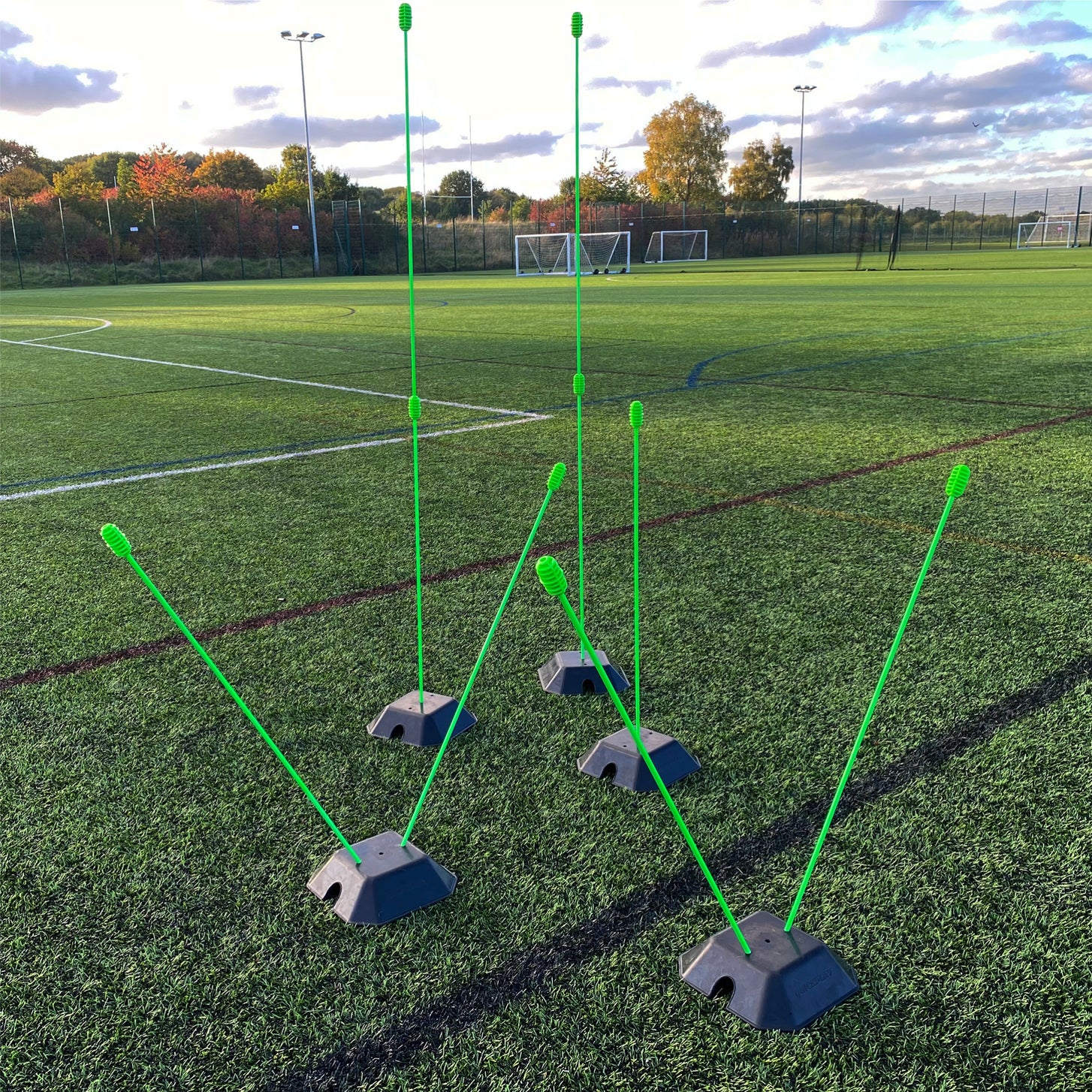 Green poles of different heights and angles set in black QUICKPLAY base weights on an artificial pitch.