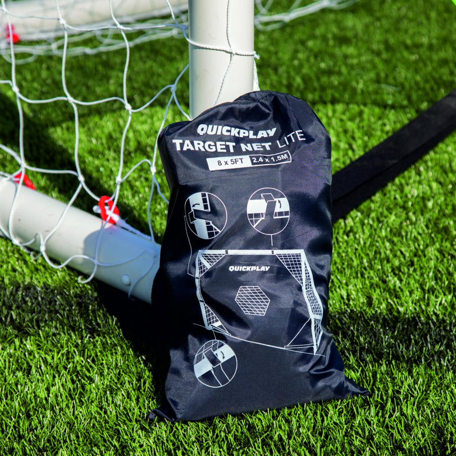 Black QUICKPLAY TARGET Net Lite storage bag printed with fitting diagrams, resting against a white goal post.