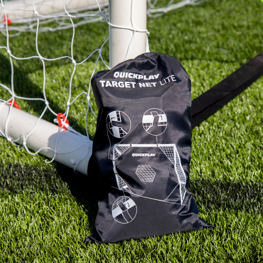 Black QUICKPLAY TARGET Net Lite storage bag printed with fitting diagrams, resting against a white goal post.